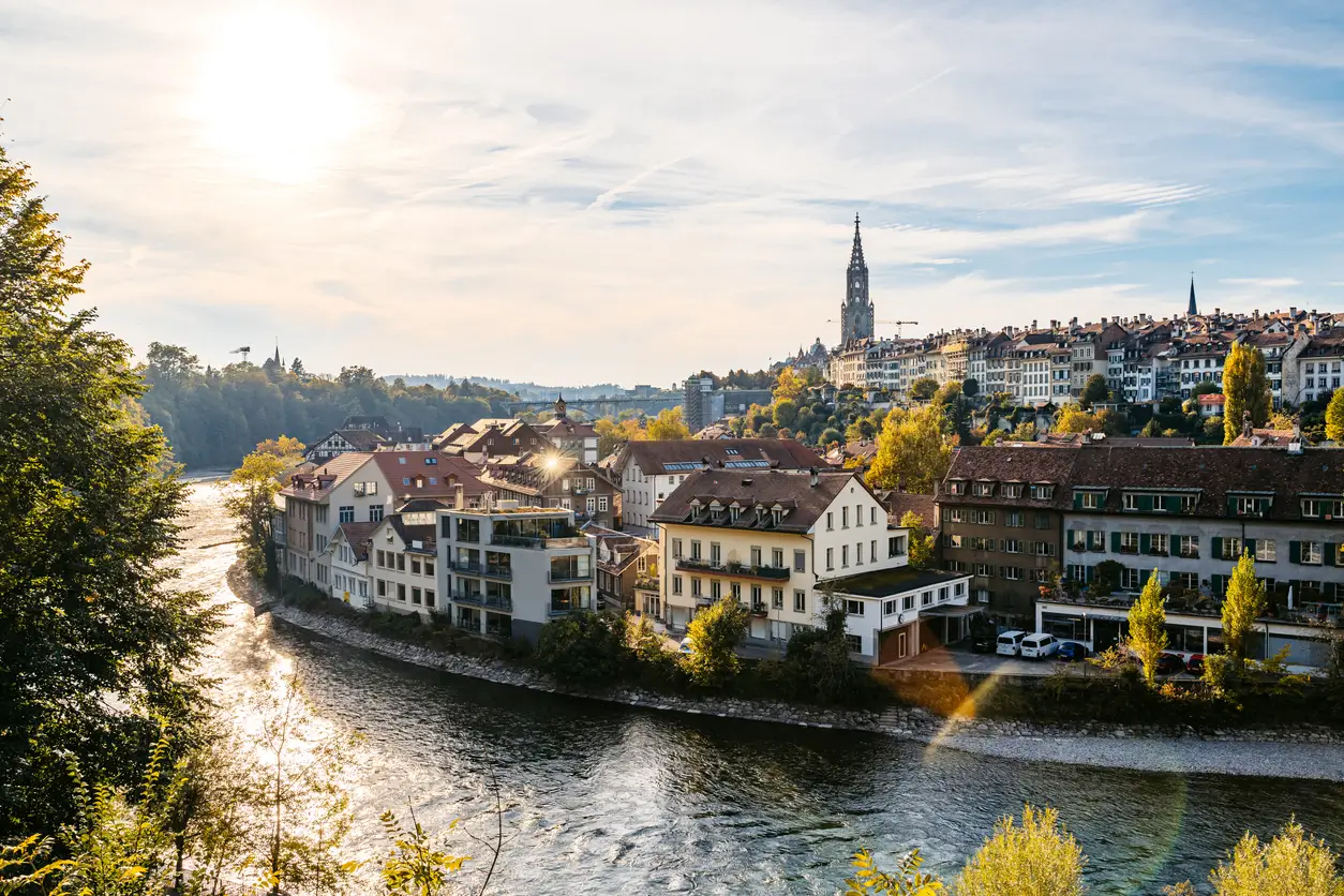 Sonnenbeschienene Häuser am Flussufer und historische Gebäude in der Nähe der besten Privatschule in einer europäischen Stadt.
