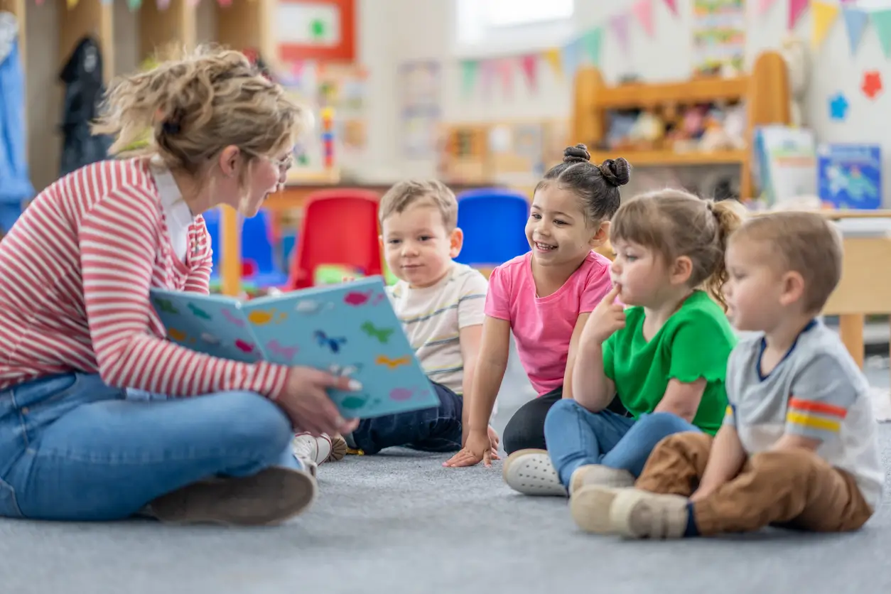 Eine Lehrerin an einer Schule in Aarau liest vier kleinen Kindern im Klassenzimmer ein Buch vor. Eine Lehrerin an einer Schule in Aarau liest vier kleinen Kindern im Klassenzimmer ein Buch vor.