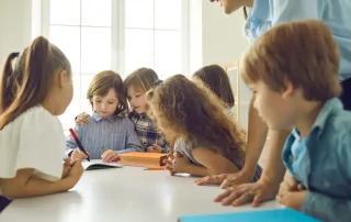 Eine Gruppe von Kleinkindern arbeitet an einem Tisch in einem Klassenzimmer einer Schule in Aarau zusammen.